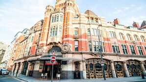 A historic building with ornate architectural details, a prominent corner entrance, and a sign indicating a restaurant. - OYO Grand Central (Liverpool)