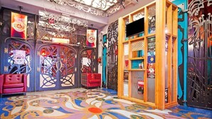 A vibrant room with a colorful floor pattern, a red chair, and a wooden display cabinet with various items. - OYO Grand Central (Liverpool)