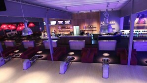 A bowling alley with multiple lanes, seating areas, and a bar in the background. - Hotell Södra Berget (Sundsvall)