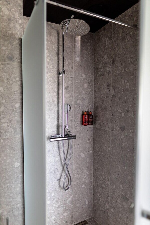 A modern shower with a handheld showerhead and a wall-mounted faucet. - Hotell Södra Berget (Sundsvall)
