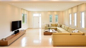 Ein modernes Wohnzimmer mit Flachbildfernseher, einem beigefarbenen Ecksofa, einem Couchtisch und einem TV-Schrank.