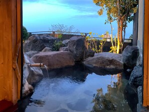 Un aménagement aquatique intérieur paisible, doté d’un bec en bambou, entouré de gros rochers et d’une rambarde en bois.