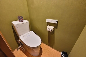 Sanitário com porta-lenços de papel estampado com flores, dispensador de toalhas de papel e uma tomada na parede.