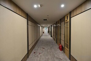 A long, narrow hallway with doors on both sides, a fire extinguisher on the right, and a carpeted floor. - Jinshi Building Hotel（Yuegezhuang Bridge, Beijing West Railway Station） (Beijing)
