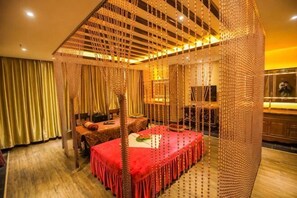 Una cama con dosel cubierta con un edredón rojo, suelo de madera y un telón de fondo de cortina.