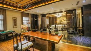 Quarto com mesa de jantar de madeira, cadeiras, um candelabro e um espelho decorativo.