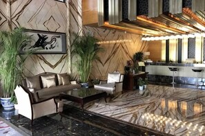A lobby with a sofa, armchairs, a coffee table, and potted plants. - Jinshi Building Hotel（Yuegezhuang Bridge, Beijing West Railway Station） (Beijing)