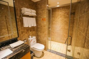 A bathroom with a marble sink, a toilet, a glass-enclosed shower, and a towel rack with folded towels. - Jinshi Building Hotel（Yuegezhuang Bridge, Beijing West Railway Station） (Beijing)