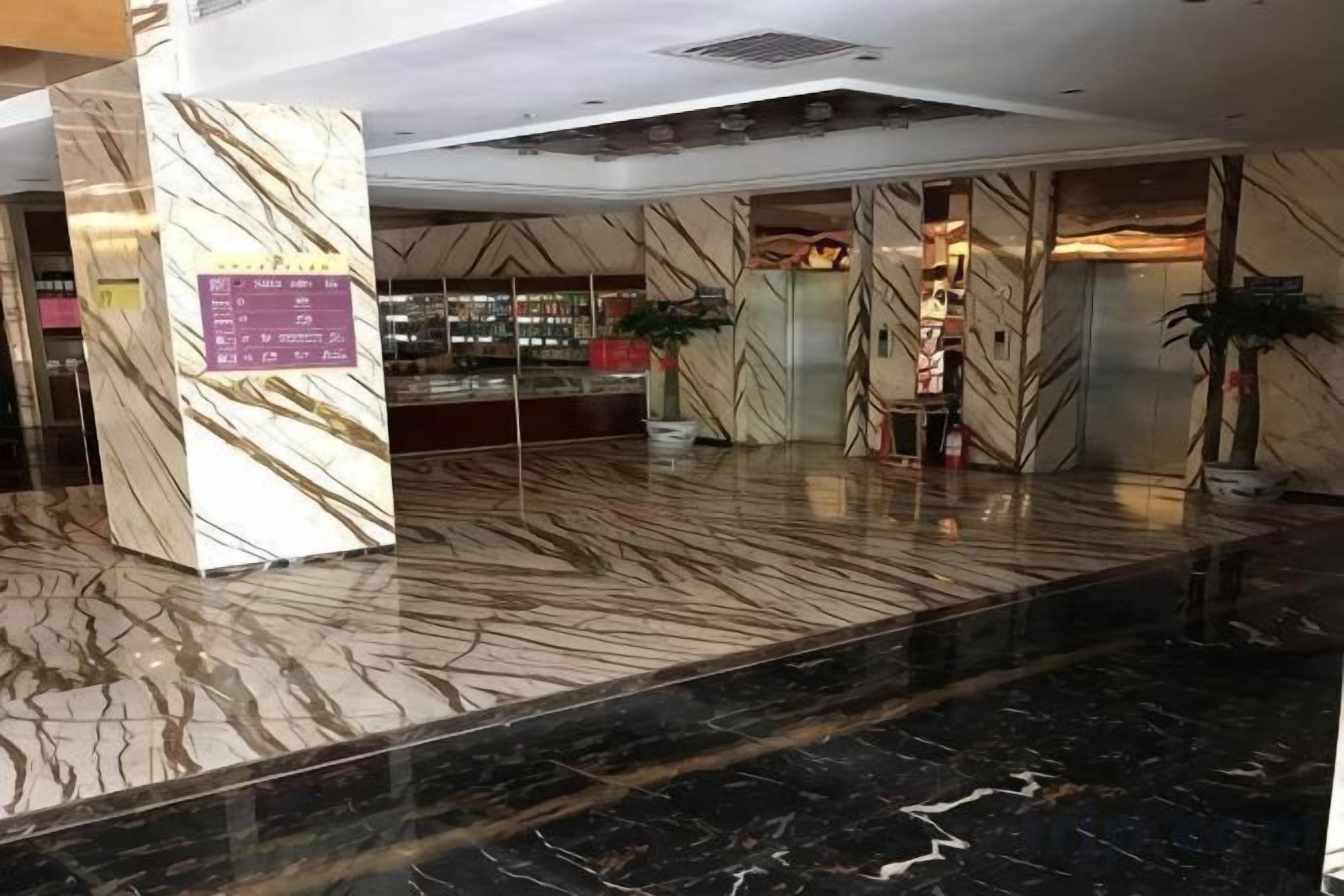 A lobby with marble flooring, a reception desk, and a plant.