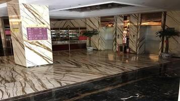 A lobby with marble flooring, a reception desk, and a plant.