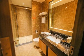 A modern bathroom with a glass shower enclosure, a marble-tiled wall, a large mirror, and a black countertop with a sink and vanity. - Jinshi Building Hotel（Yuegezhuang Bridge, Beijing West Railway Station） (Beijing)