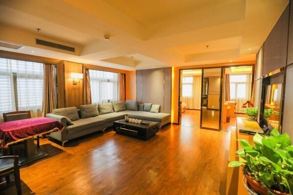 A modern living room with a sectional sofa, a coffee table, and a dining area with a table and chairs. - Jinshi Building Hotel（Yuegezhuang Bridge, Beijing West Railway Station） (Beijing)
