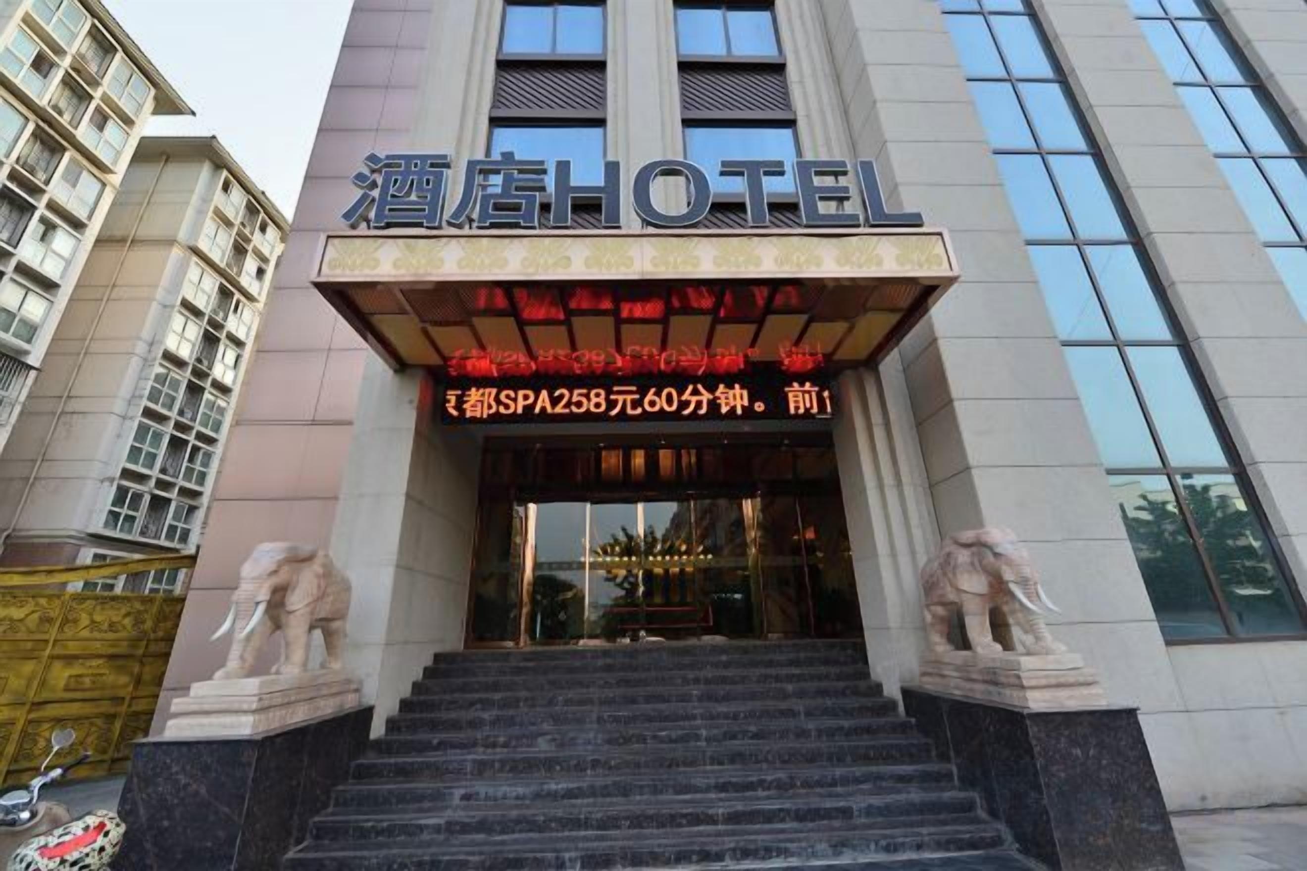 A hotel entrance with a staircase, a signboard, and two statues.