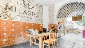 A hotel lobby with a rustic brick wall, a wooden reception desk, and a patterned ceiling. - Milagro Hotel (Puebla)