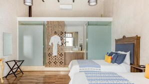 A hotel room with a wooden floor, a bed with a patterned bedspread, a nightstand, and a wooden headboard. - Milagro Hotel (Puebla)