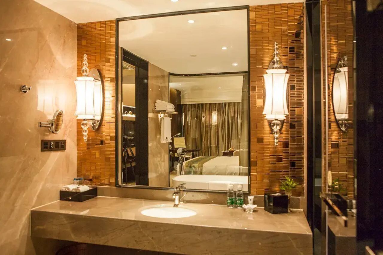 Un baño moderno con un espejo grande, un lavamanos y dos luces empotradas.