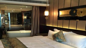 Een moderne hotelkamer met een groot bed, een badkamer met glazen wanden en een decoratief paneel.