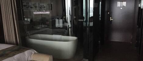 Habitación de hotel con una bañera grande, una cama y un box de ducha de vidrio.