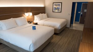 Una habitación de hotel con dos camas, una mesita de noche, una lámpara y un cuadro en la pared.