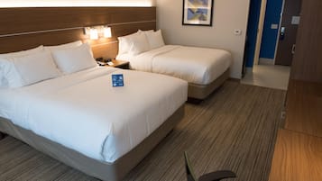 Ein Hotelzimmer mit zwei Betten, einem Nachttisch, einer Lampe und einem gerahmten Bild an der Wand.