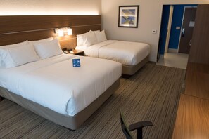 Une chambre d’hôtel avec deux lits, une table de chevet, une lampe et un tableau encadré au mur.