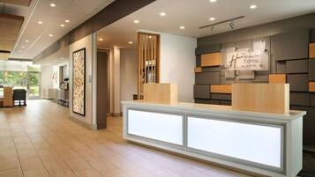 Un espace d’accueil moderne, avec un comptoir de réception, une enseigne indiquant « Holiday Inn Express & Suites » et une vue sur l’extérieur.
