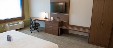 A hotel room with a bed, a desk with a chair, a TV, and a wardrobe.