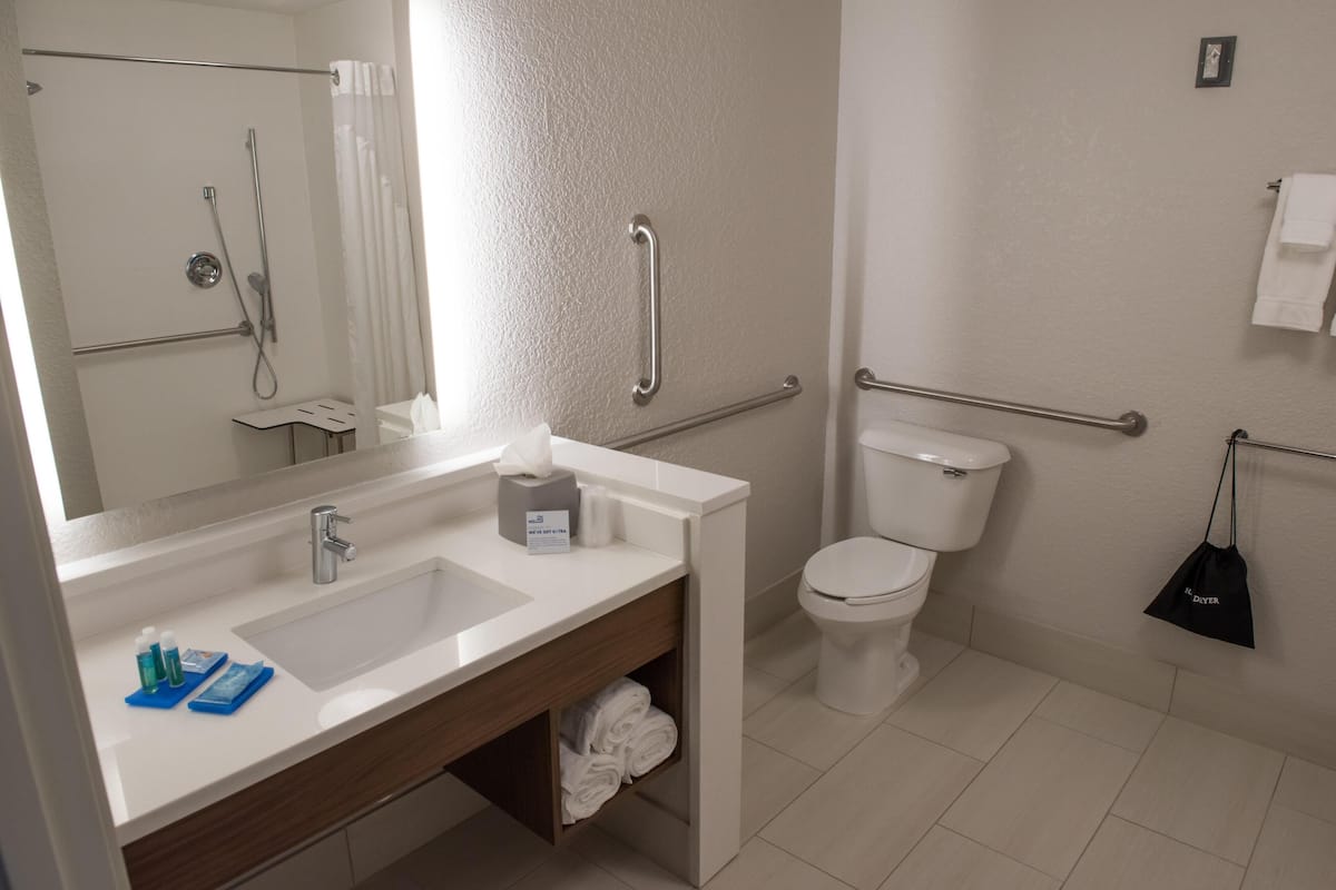 A modern bathroom with a sink, mirror, toilet, and shower.