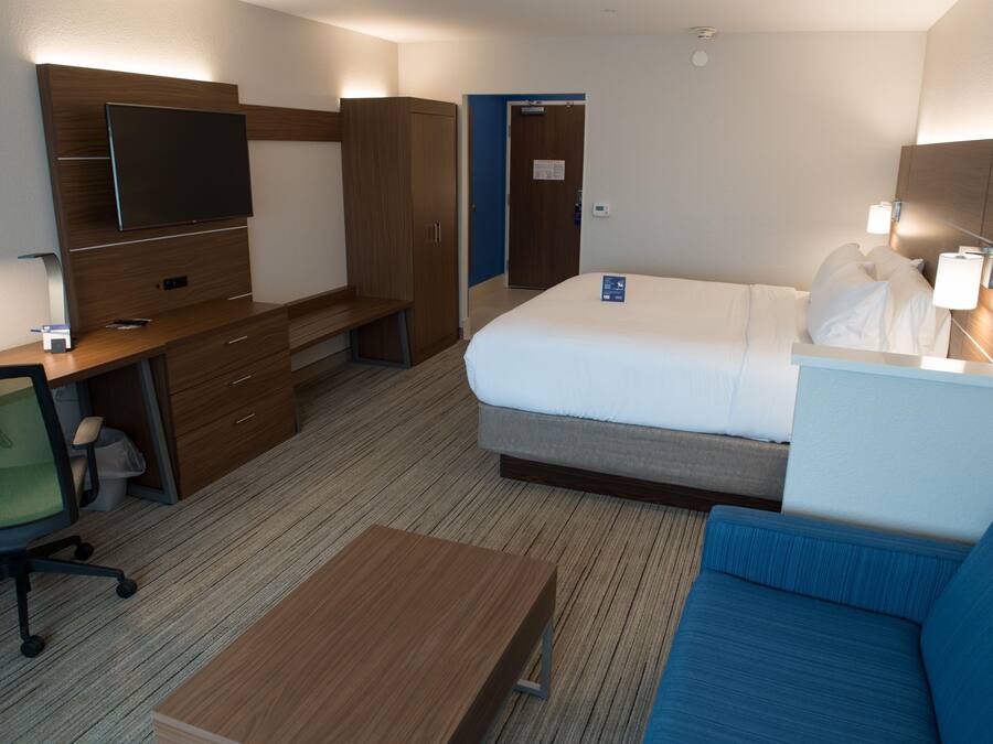 Une chambre d’hôtel comprenant un lit, un bureau avec une chaise, une télévision et un canapé.