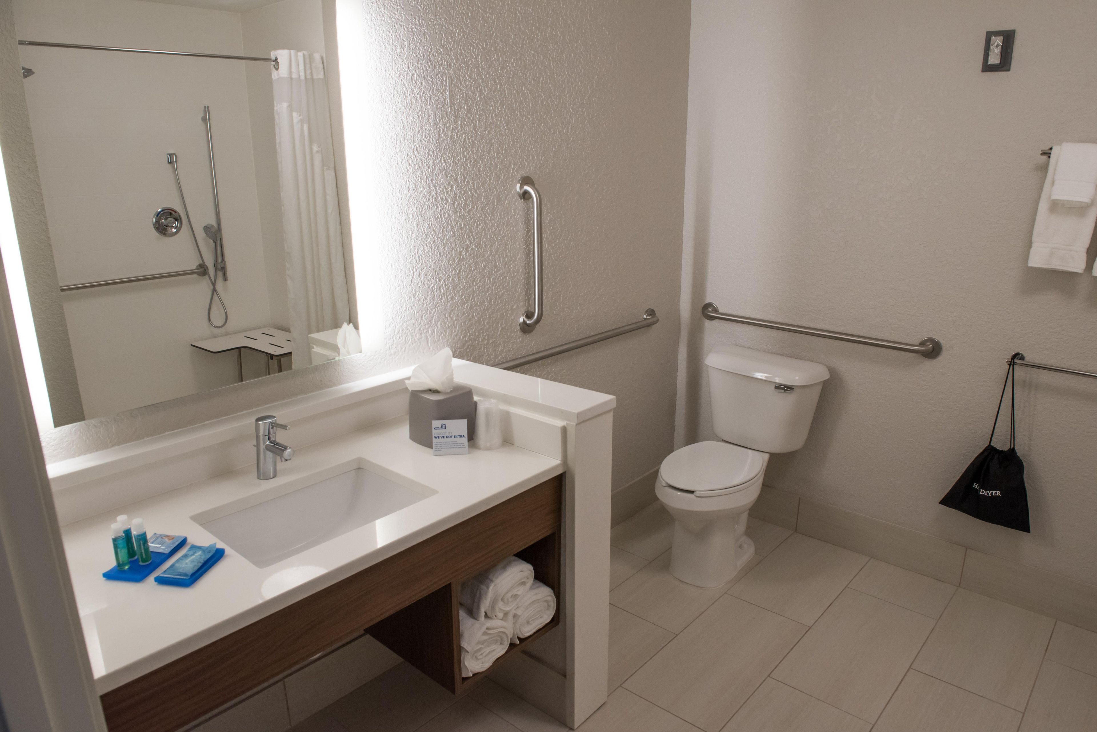 A modern bathroom with a sink, mirror, toilet, and shower.