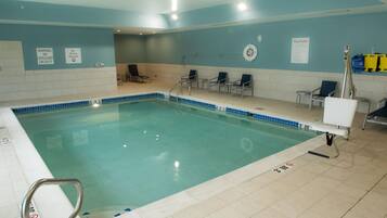A swimming pool with clear water, a lifeguard chair, and lounge chairs.