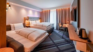 A hotel room with two beds, a desk, a chair, a TV, and a window with curtains. - Premier Inn Munich Airport Sud Hotel (Hallbergmoos)