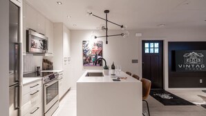A modern kitchen with a central island, stainless steel appliances, and a pendant light.