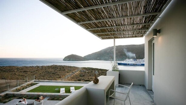 A modern balcony with a view of the sea and a ship.