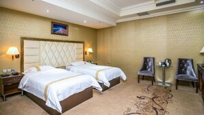 A hotel room with two beds, a large headboard, two chairs, a small table, and a decorative rug. - Yugang Zhizun Hotel (Dalian)