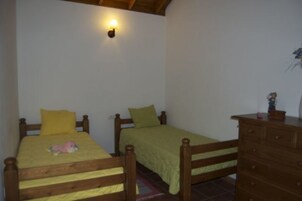 Un dormitorio con dos camas individuales, cabeceros de madera, una mesita de noche y un aparador.