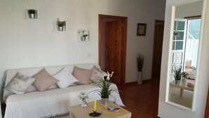 Una sala de estar con un sofá, una mesa de centro y una puerta que da a otra habitación.
