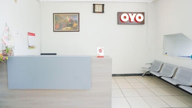 Zona de recepción con mostrador, un reloj, un cuadro enmarcado y un cartel que dice "OYO".