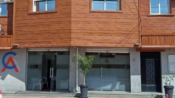 A hotel with a wooden facade, a glass entrance, and a logo on the left. - Costa Ayaa Appart Hotel (Algiers)