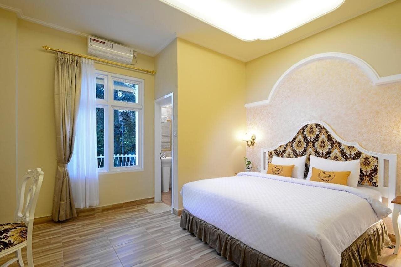 A bedroom with a bed, curtains, a chair, and a window.