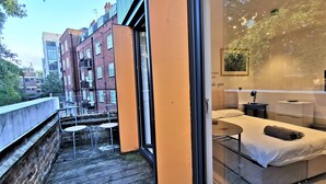 Ein modernes Hotelzimmer mit Balkon, einem Bett und einer kleinen Sitzecke.