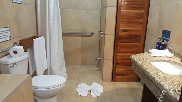 A bathroom with a toilet, shower, and sink.