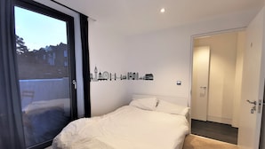 A bedroom with a large window, a bed, and a door. - Double Room with Balcony - 3c (London)