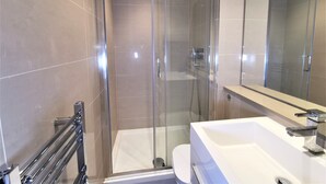 A modern bathroom with a glass-enclosed shower, a white sink, and a large mirror. - Double Room with Balcony - 3c (London)