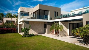 A modern two-story house with a stone facade, large windows, and a well-maintained lawn. - Private Luxury Escape, Cabo San Lucas Villa 1048 (Cabo San Lucas)