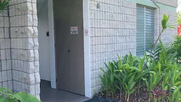 A building entrance with a gated door, a small garden area with plants, and a paved pathway leading to the door.