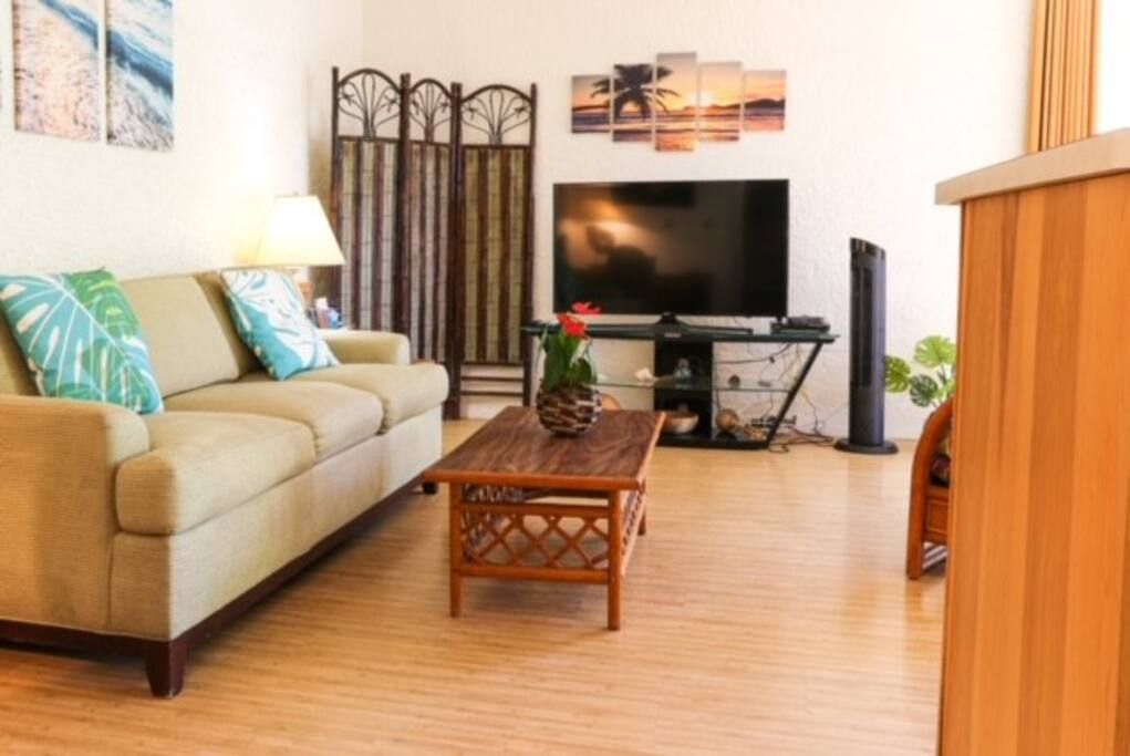 Sala de estar com sofá, mesa de centro, televisão e objetos decorativos.