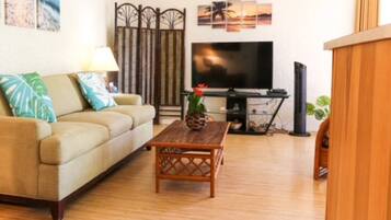 Sala de estar com sofá, mesa de centro, televisão e objetos decorativos.