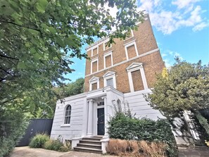 A two-story building with a white facade and a brick upper level. - Spacious 2 bed flat in Camden (London)