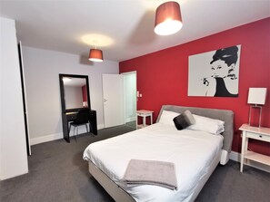 A bedroom with a bed, a desk with a chair, a mirror, a bedside table, and a lamp. - Spacious 2 bed flat in Camden (London)